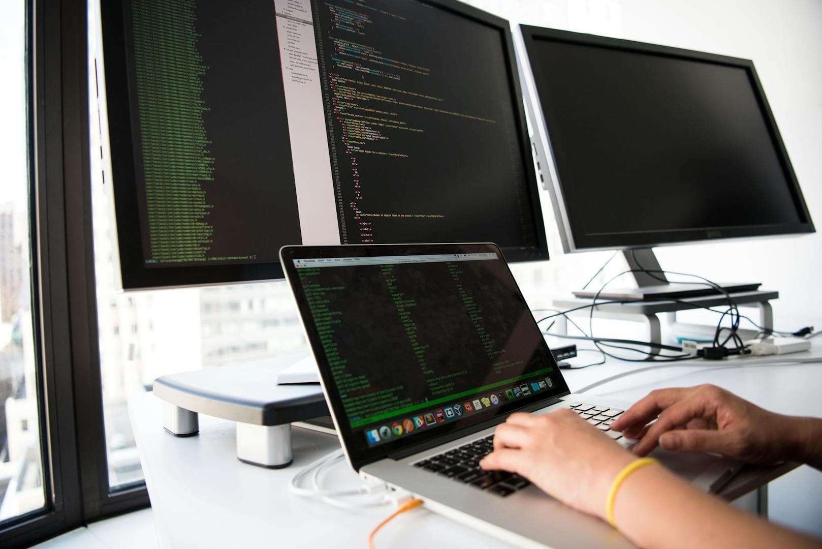 Developer working on code with multiple screens